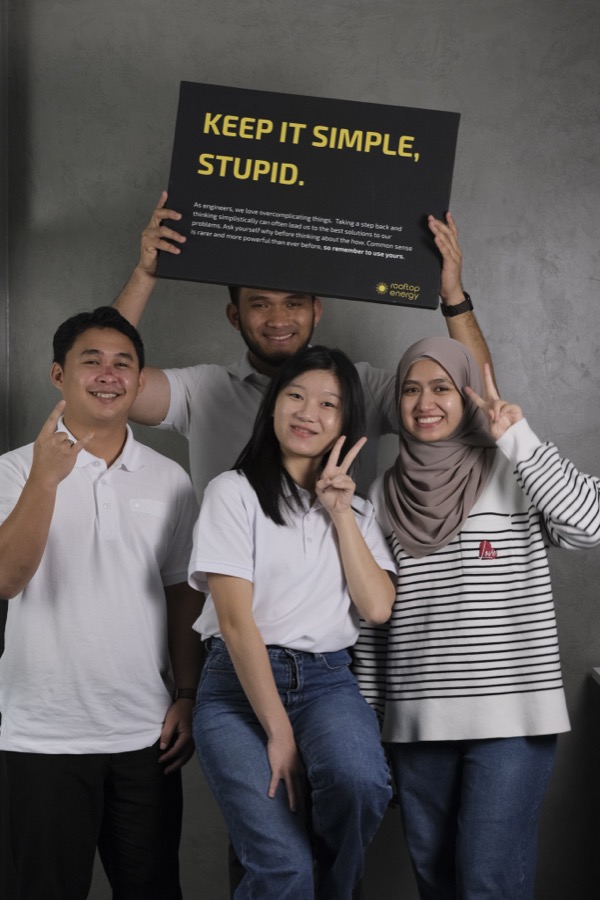 Rooftop Energy team members holding a Keep It Simple, Stupid sign.